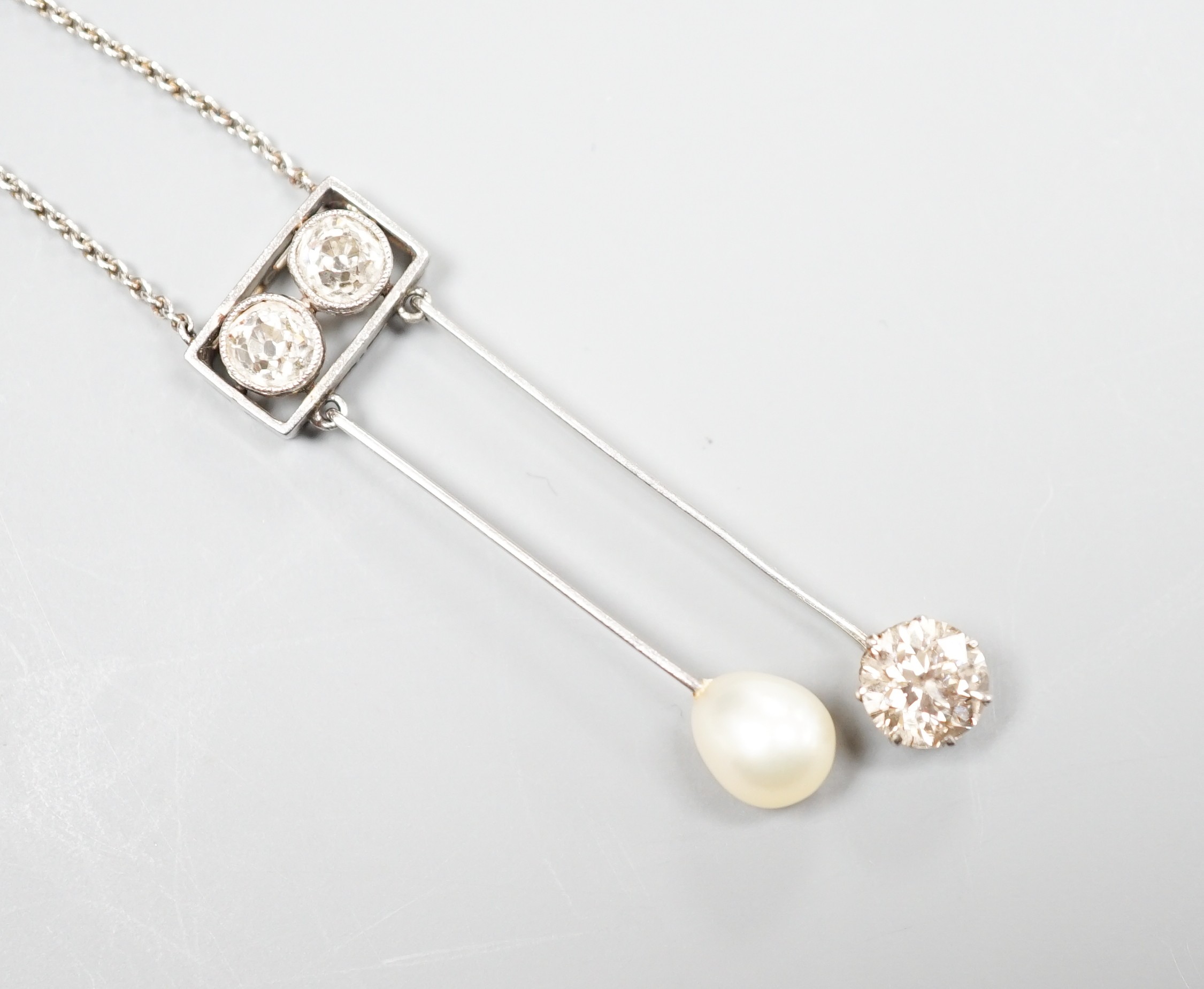 A 1940's white metal (probably platinum), three stone diamond and single stone teardrop shaped pearl set double drop pendant necklace, pendant 39mm, chain 41cm, gross weight 5.9 grams.